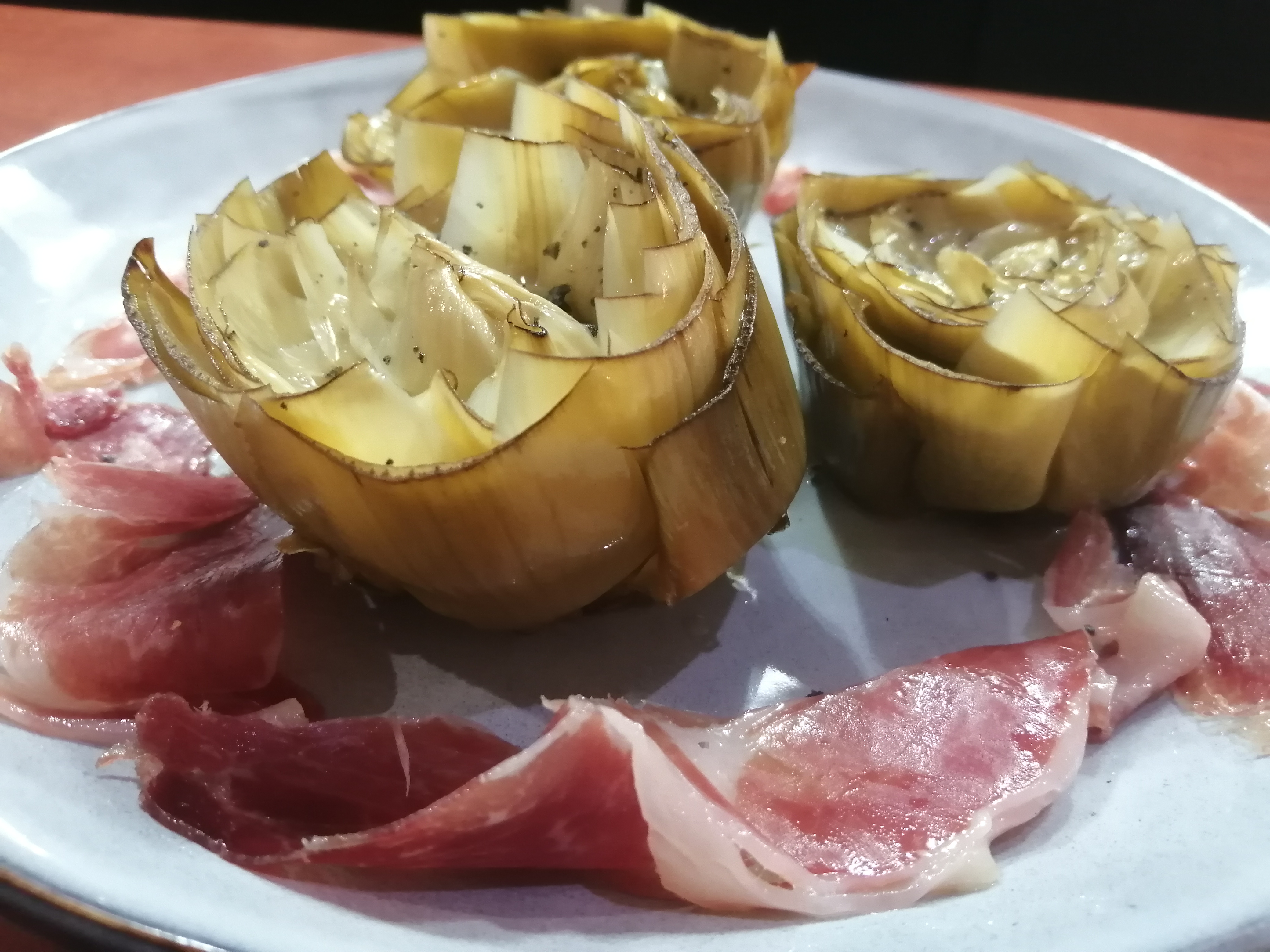 Carxofes confitades amb pernil ibèric i oli de brasa.